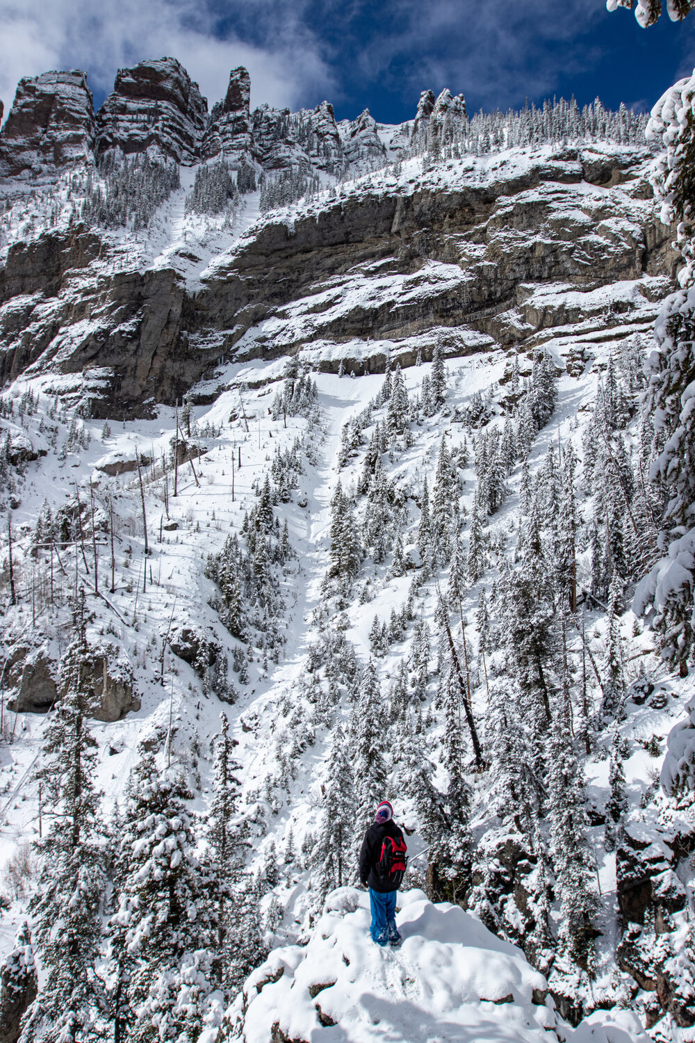 A picture of a man walking up a wintery slope